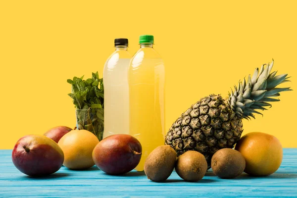 果汁饮料在塑料瓶和新鲜成熟热带水果在绿松石木桌顶部 — 图库照片