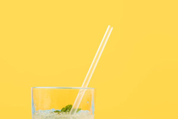 close-up view of glass with fresh cold summer cocktail and drinking straw isolated on yellow