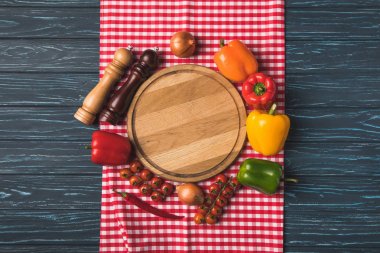 top view of ripe organic vegetables and pepper grinders around wooden board on table clipart