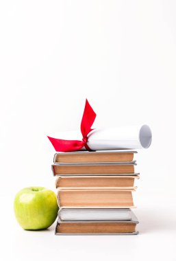 Diploma on pile of books and apple isolated on white clipart