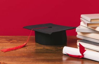 Cropped image of pile of books with diploma and academic cap on red clipart