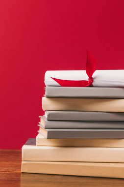 Cropped image of diploma on top of stack of books on red clipart