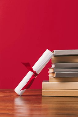 Cropped view of stack of books and diploma on red clipart