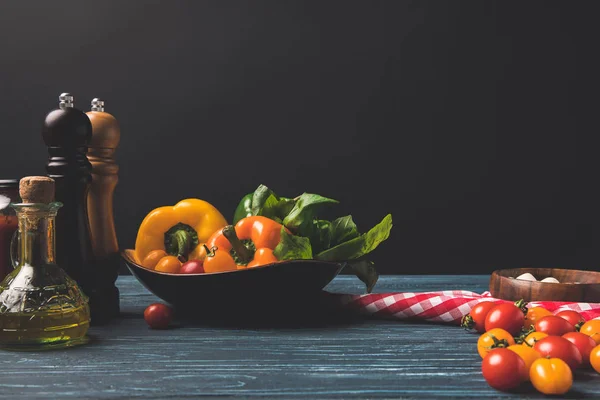 ピーマン チェリー トマトと黒に分離されたキッチンの木製テーブルでオイル — ストック写真