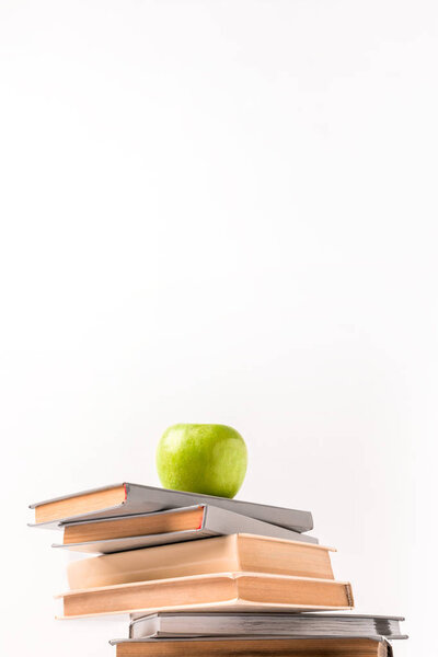 Low angle view of pile of books with apple on top isolated on white