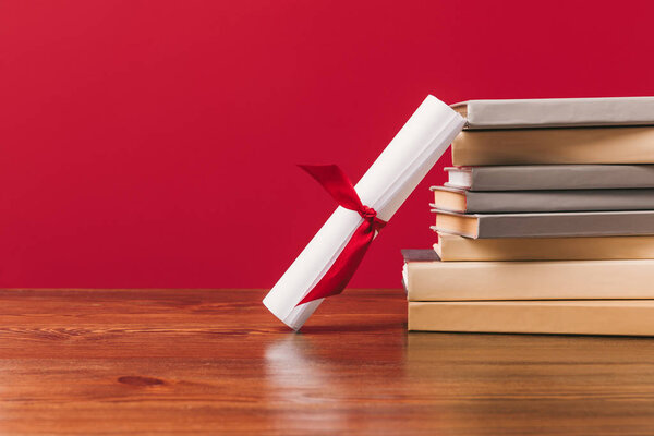 Diploma and stack of different books on red