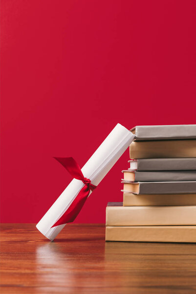 Cropped view of stack of books and diploma on red