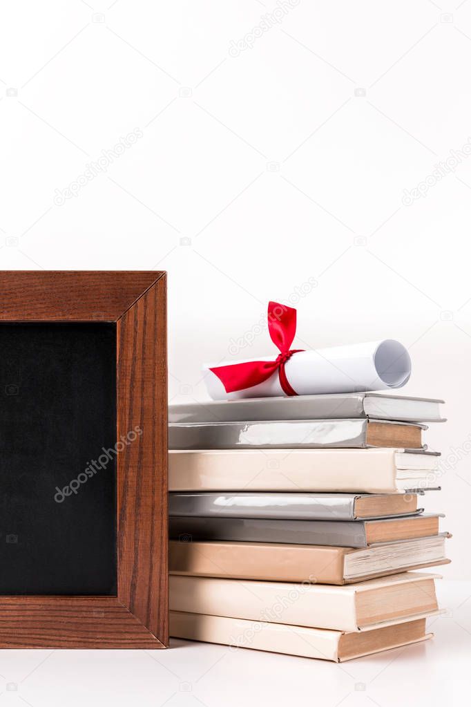 Diploma on stack of books with empty blackboard isolated on white