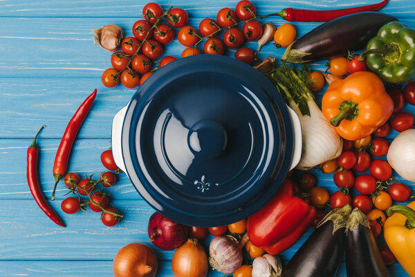 top view of pan between vegetables on blue table