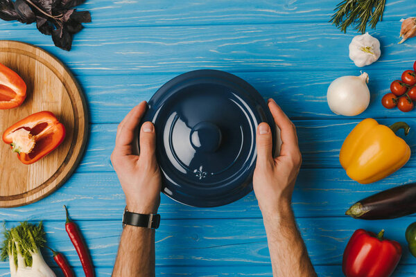 cropped image of man putting pan on blue table