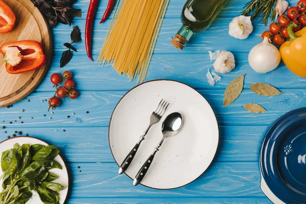 青テーブルにフォークとスプーンと野菜プレートの上から見る — ストック写真