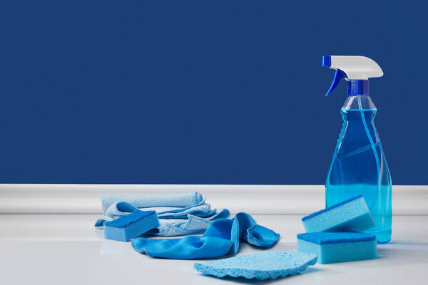 blue spray, rags and washing sponges for spring cleaning on white floor