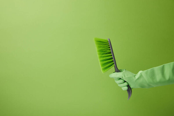 обрезанный образ человека, держащего кисть для весенней очистки изолированы на зеленый
