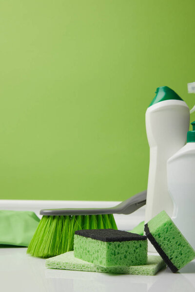 green brush, washing sponges and bottles of liquids for spring cleaning