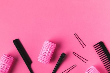 Pembe üzerinde curlers, tarak ve kuaförlük araçları, üstten görünüm