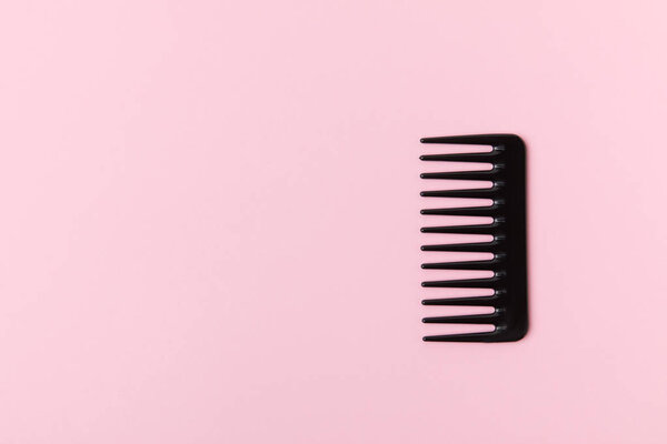 one black comb, isolated on light pink