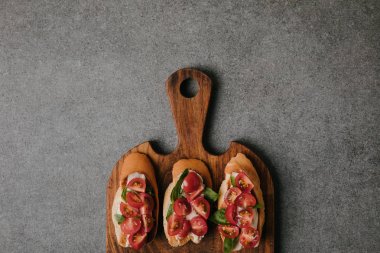 top view of gourmet italian bruschetta on wooden cutting board on grey   clipart