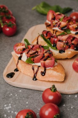 close-up view of tasty healthy bruschetta with tomatoes and balsamic on wooden board clipart