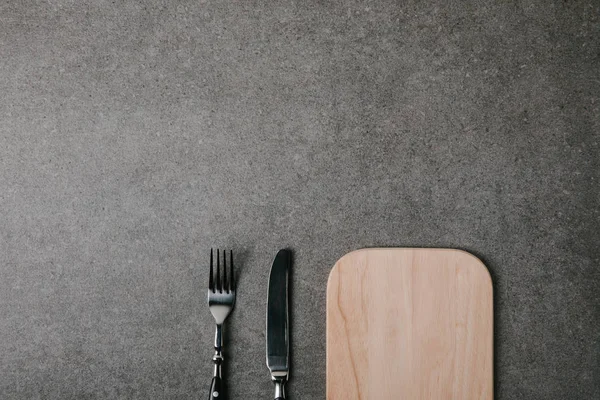 Bovenaanzicht Van Houten Plank Met Mes Vork Grijze Achtergrond — Stockfoto