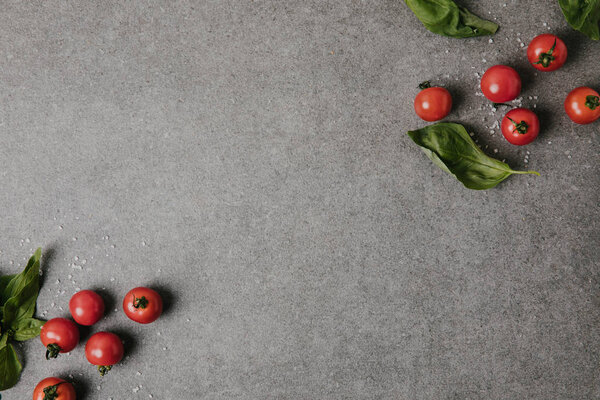 top view of fresh tomatoes, basil and salt on grey background