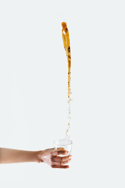 cropped view of hand holding glass and big splash of coffee, isolated on white