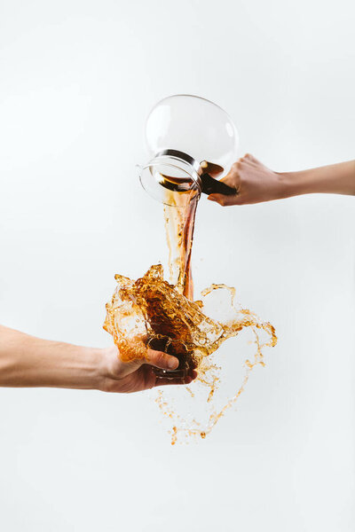 cropped view of hand splashing coffee from glass pot, isolated on white