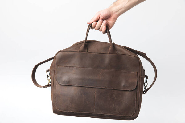 частичный вид человека, держащего стильную сумку в руке изолированы на белом
