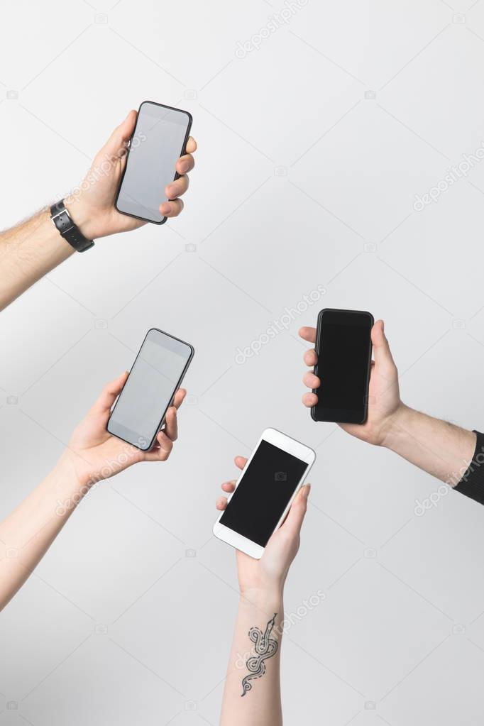 partial view of group of people with smartphones with blank screens isolated on white