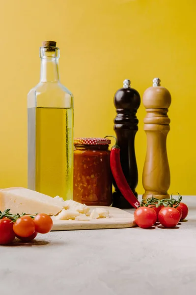 cherry tomatoes with cheese and spices for pasta on concrete tabletop, ingredients of italian cuisine