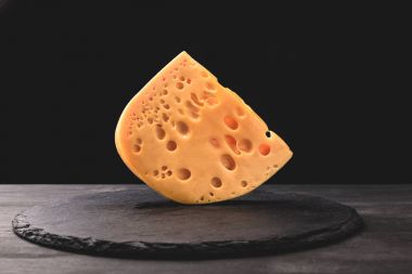 Close up shot of emmental cheese on board on black clipart