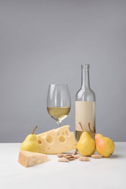Cheddar and maasdam cheese, pears, almond, wine glass and bottle on gray clipart