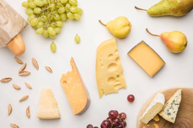Top view of different types of cheese, grapes, pears, almond and baguette on white  clipart