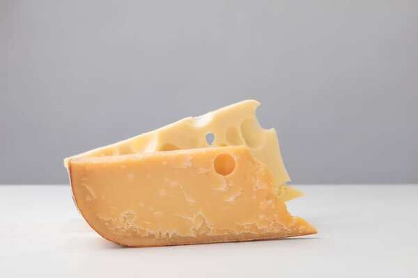 Close up view of parmesan and maasdam cheese on gray