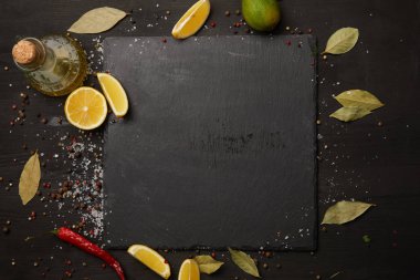 Dark slate board with spices and lemon slices clipart