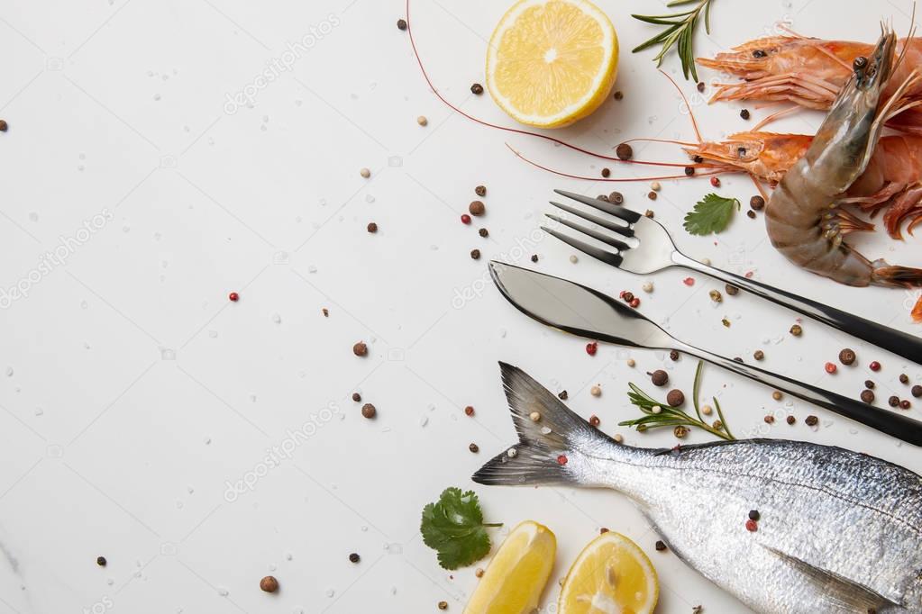 Shrimps and fish with spices and silverware isolated on white