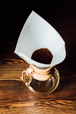 Top view of chemex with ground coffee in filter cone on wooden table  clipart