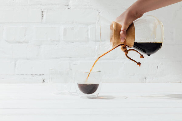 Cropped shot of woman pouring alternative coffee from chemex into glass mug 