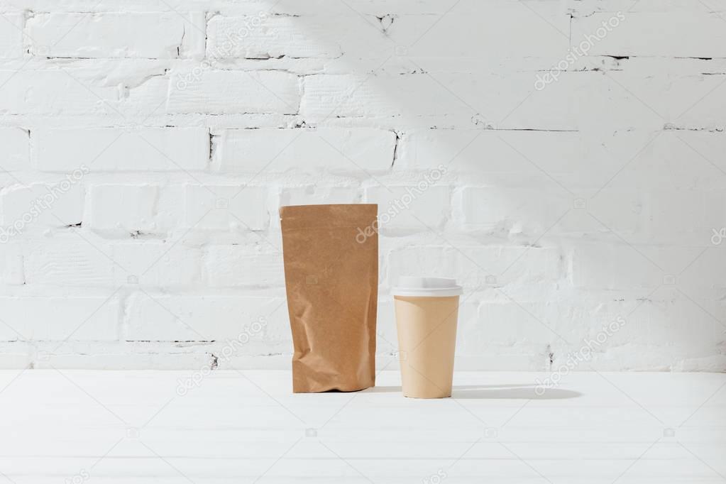 Front view of paper package of coffee and disposable cup