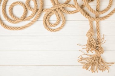 top view of brown nautical knotted rope on white wooden background clipart