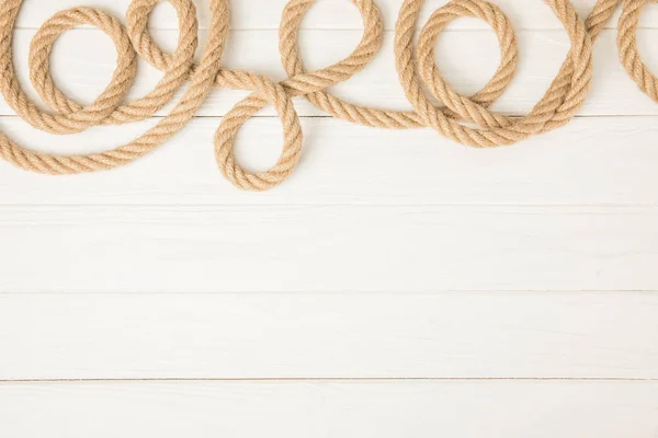 top view of brown nautical rope on white wooden background