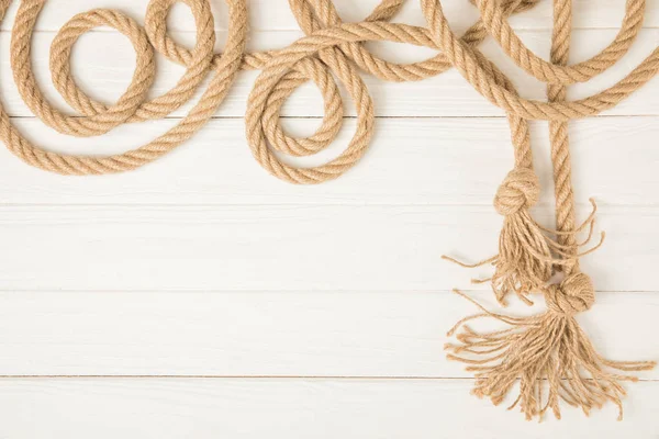 白い木製の背景に茶色の航海結び目ロープの上から見る — ストック写真