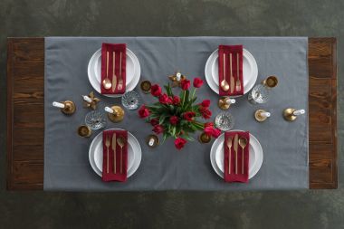 rustik Tablo ayarı kırmızı lale buketi, kararmış çatal bıçak takımı, şarap gözlük, mumlar ve iki boş tabak ile masa üzerinde yukarıdan