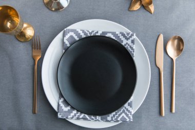 top view of black empty plate, napkin and old fashioned tarnished cutlery on tabletop clipart