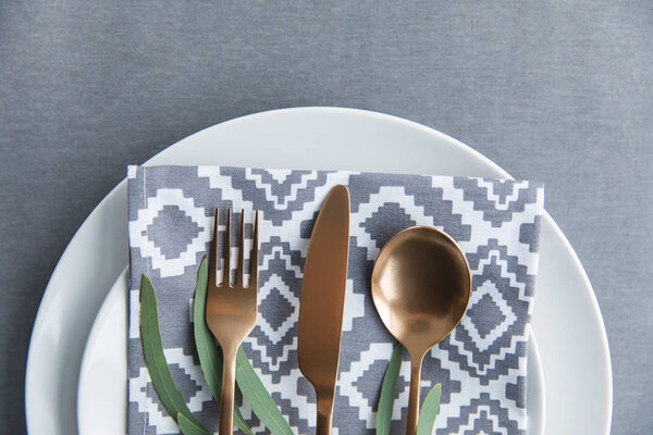 flat lay with rustic table setting with vintage tarnished silverware, napkin, green plant and plate