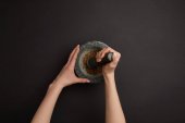 partial view of woman with mortar and pestle on black surface