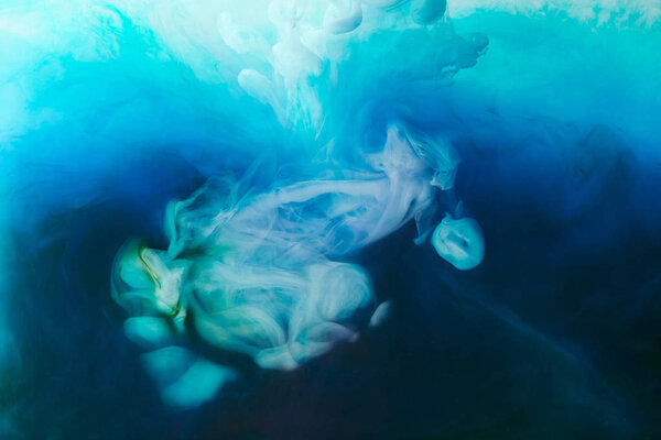 Full frame image of mixing of blue, turquoise, black and white inks splashes in water