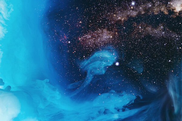 full frame image of mixing turquoise, blue and black paint splashes in water with universe background