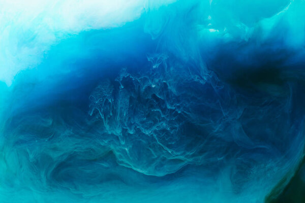 full frame image of mixing of blue, black, turquoise and white paints splashes in water