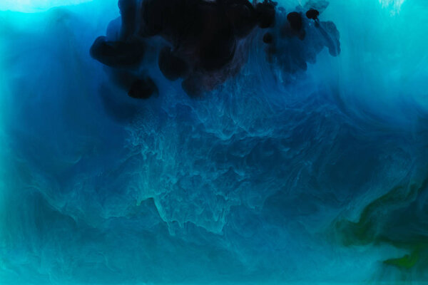 full frame image of mixing of blue, black, turquoise and green paints splashes in water