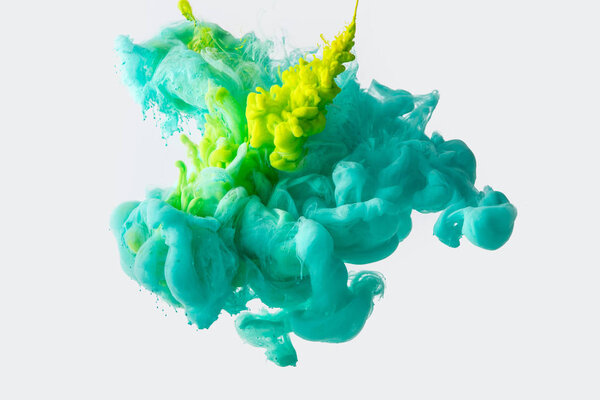 Close up view of mixing of green and bright turquoise ink splashes in water isolated on gray